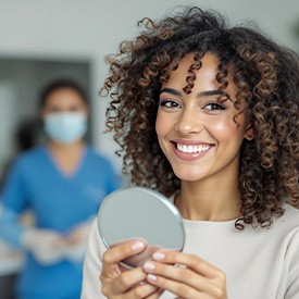 Woman smiling while holding small mirror