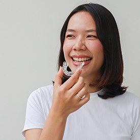 Woman smiling while holding clear aligner