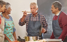 Groups of friends making a meal together while one of them taste-tests